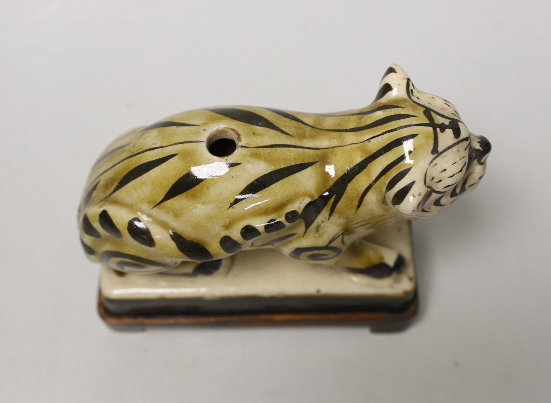 A Chinese Cizhou style pottery ‘tiger’ incense stick holder on wood stand, 13cm tall